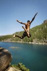 Jeune homme sautant dans le lac — Photo de stock