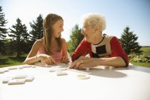 Бабушка и внучка вместе играют в домино — стоковое фото