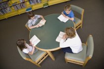 Grupo de niños pequeños leyendo en la biblioteca - foto de stock