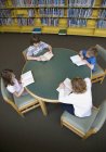 Grupo de niños pequeños leyendo en la biblioteca - foto de stock