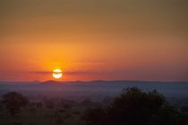 Pôr do sol sobre o campo com colinas — Fotografia de Stock