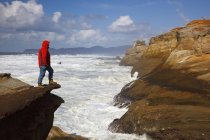 Тихоокеанський місто штату Орегон, Сполучені Штати Америки; Чоловік, що стоїть на краю скелі вздовж узбережжя на мисі Kiwanda — стокове фото