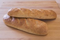 Dos panes de pan al horno en el primer plano de la tabla de cortar - foto de stock