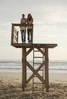 Mother and daughter on wooden tower at Los Lances beach at sunset in Tarifa, Spain — Stock Photo