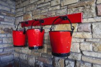 Sabots rouges vintage suspendus au mur de pierre — Photo de stock