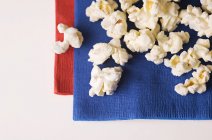 Primo piano vista dall'alto di popcorn su tovaglioli blu e rossi — Foto stock