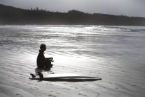 Surfista meditando en la playa - foto de stock