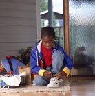 Афроамериканский мальчик привязывает новую обувь — стоковое фото