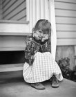 Retrato monocromático de la chica sentada en el porche y mirando a la cámara - foto de stock