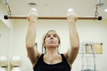 Caucásico mujer usando bar durante el ejercicio en el gimnasio - foto de stock