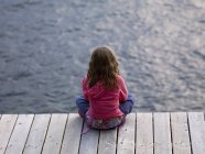 Rear view of girl sitting on dock — Stock Photo