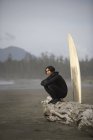 Surfista sentado en la playa - foto de stock