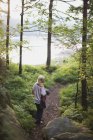 Chica caminando por el bosque hasta el lago; Kristiansand, Noruega - foto de stock