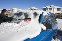 Uomo spazzolare la neve dal parabrezza di un veicolo; Calgary, Alberta , — Foto stock