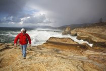 Pazifikstadt, oregon, vereinigte staaten von amerika; ein mann, der am kap kiwanda an der küste entlang geht — Stockfoto