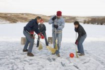 Feliz caucásico familia en invierno fin de semana jugando en bola con escobas - foto de stock