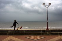 Hombre con paraguas de pie junto al paseo marítimo, Yorkshire, Inglaterra - foto de stock