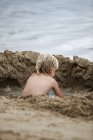 Un niño juega en la arena junto al agua; Currumbin, Gold Coast, Queensland, Australia - foto de stock