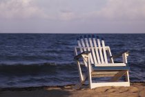 Uma cadeira de madeira na praia — Fotografia de Stock