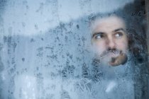 Young Man Looking Out A Frosted Window — Stock Photo