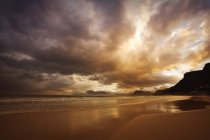 Puesta de sol sobre la playa nublada - foto de stock