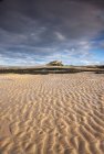 Castillo de Bamburgh sobre una playa de arena - foto de stock