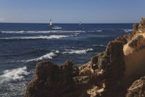 Barche a vela Crociera lungo le formazioni costiere — Foto stock