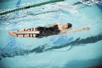 Mujer parapléjica nadando en la piscina espalda - foto de stock