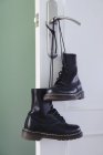 Paar schwarze Stiefel, die durch Schnürsenkel zusammengebunden sind und an der Türklinke hängen — Stockfoto