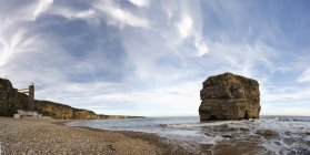 Un grand rocher au large de la côte — Photo de stock