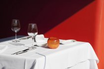 Tavola apparecchiata per cena formale contro muro rosso — Foto stock