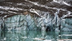 Acantilado glaciar grava reflejado en pequeño lago glacial, parque nacional de jaspe, alberta, canada - foto de stock