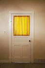 Puerta interior de casa de campo con cortinas amarillas en la ventana - foto de stock
