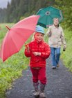 Бабушка и внучка гуляют с зонтиками вместе — стоковое фото