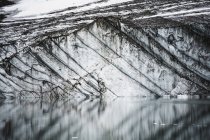 Camadas em penhasco geleira gravelly refletido em pequeno lago glacial, parque nacional jasper, alberta, canadá — Fotografia de Stock