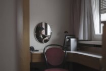 Reflexão de uma mulher em um espelho como ela olha pela janela — Fotografia de Stock