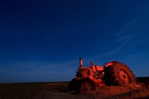 Old tractor in dirt lit with red light. Childress, Texas, USA — Stock Photo