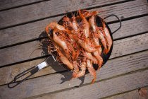Crevettes fraîches attrapées dans une casserole sur une surface en bois — Photo de stock