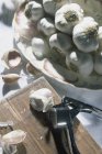 Fresh garlic heap in bowl with garlic press — Stock Photo