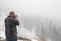 Um homem tira uma foto de uma paisagem na neve em queda; Colorado Estados Unidos da América — Fotografia de Stock