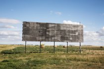 Un tabellone per le affissioni vuoto accanto a un campo agricolo — Foto stock