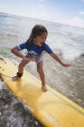 Giovane ragazza su tavola da surf gialla. Costa d'oro, Queensland, Australia — Foto stock