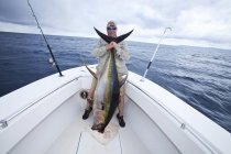 Чоловік тримає свіжий впійманий жовтофініш тунець — стокове фото