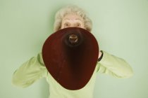 Старшая белая женщина, разговаривающая с красным мегафоном — стоковое фото