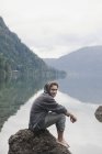 Молода людина сидить на скелі в озеро Камерон; Британська Колумбія, Канада — стокове фото
