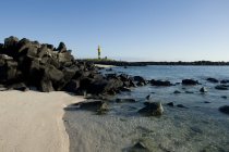 Un faro, rocce e sabbia bianca — Foto stock