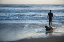 Силует людини, що стоїть на пляжі, дивлячись Out над океаном — стокове фото