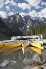 Canoas a lo largo de un muelle que refleja frente al lago - foto de stock