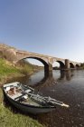 Boot am Ufer bei einer Brücke zurückgelassen — Stockfoto