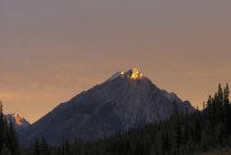 El amanecer ilumina un pico de montaña - foto de stock
